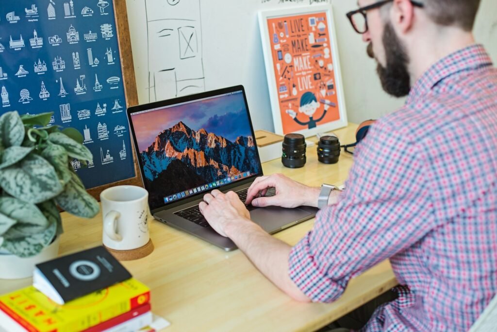 Freelancer typing at a laptop in a home office with posters and books