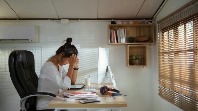 Freelancer sitting at a desk with her head in her hands in front of a monitor