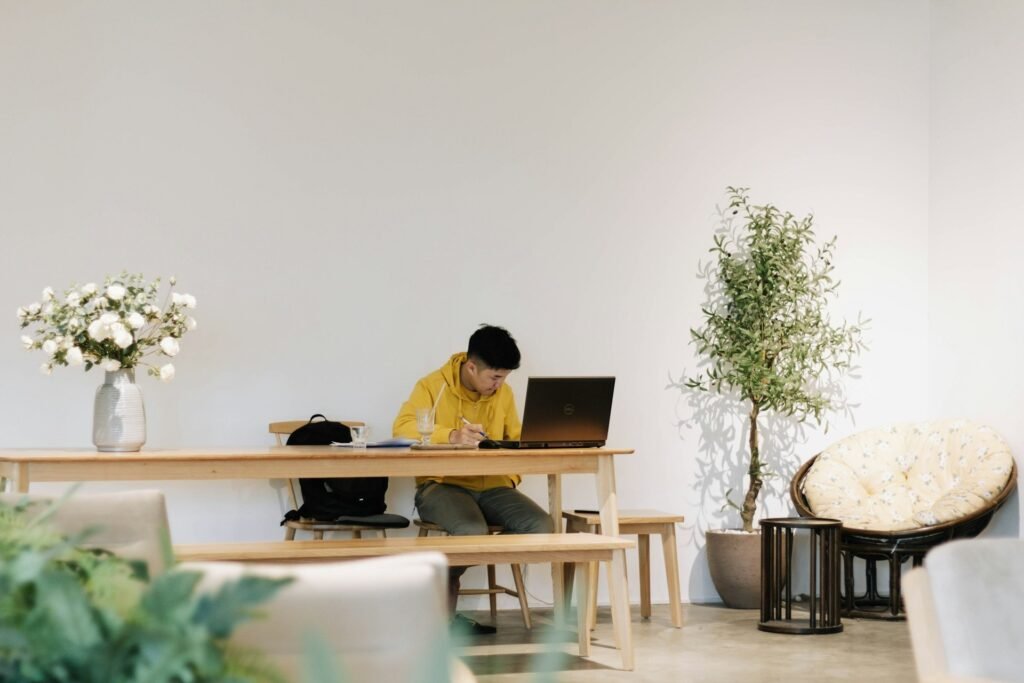 Freelancer working alone at a long wooden table in a bright, sparse room