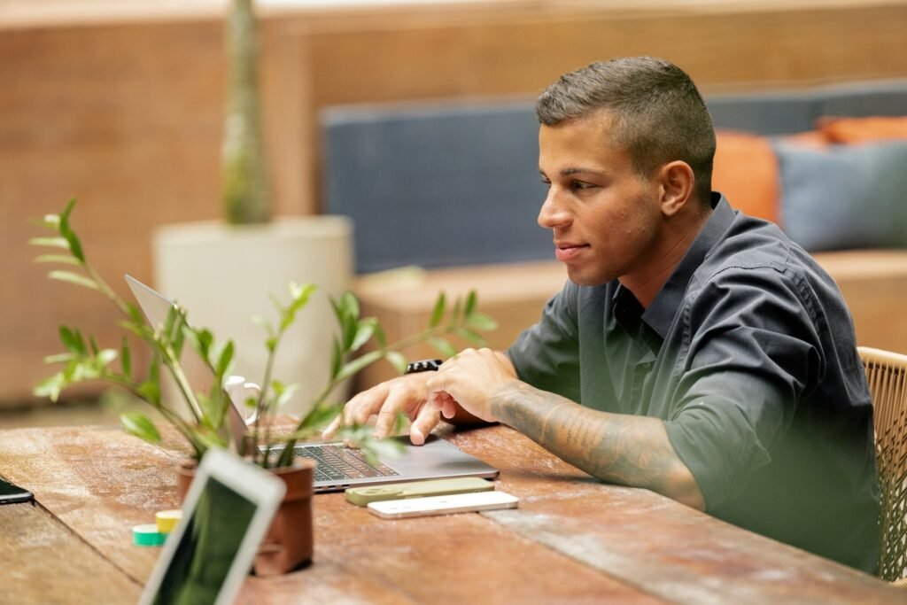 Freelancer working on a laptop at a café table with a phone beside him