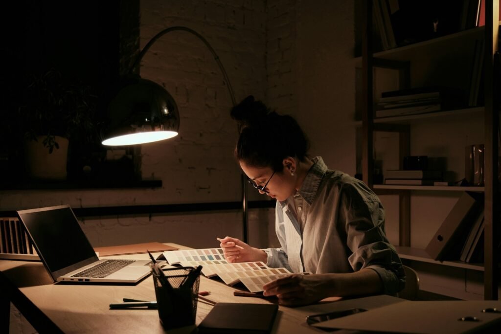 Freelancer working under a desk lamp with colour swatches spread out, working hard