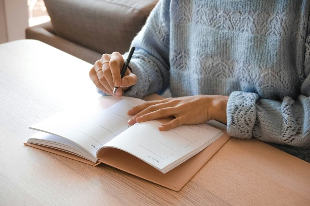 Freelancer writing into a weekly planner notebook, filling in tasks day by day